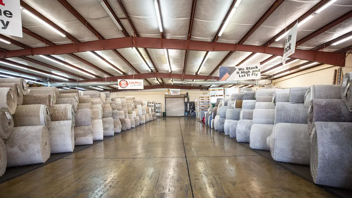 Flooring warehouse with many rolls of carpet.